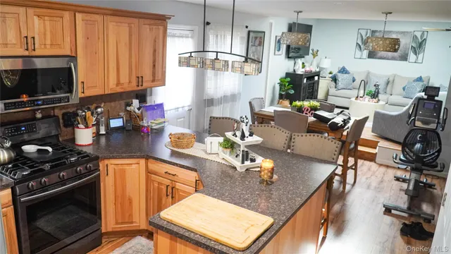 a kitchen with stainless steel appliances granite countertop a stove top oven a dining table and chairs with wooden floor