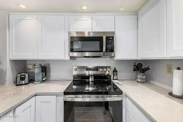 a kitchen with stainless steel appliances granite countertop white cabinets a stove a sink and dishwasher
