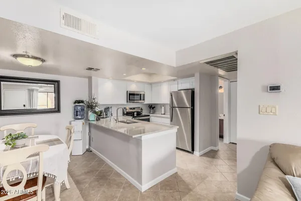 a kitchen with stainless steel appliances a refrigerator a table and chairs