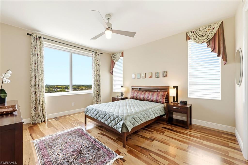 265 Indies Way, Unit 701 Naples, FL 34110 - Photo 28 of 50 a bedroom with a bed lamp and a large window with wooden floor
