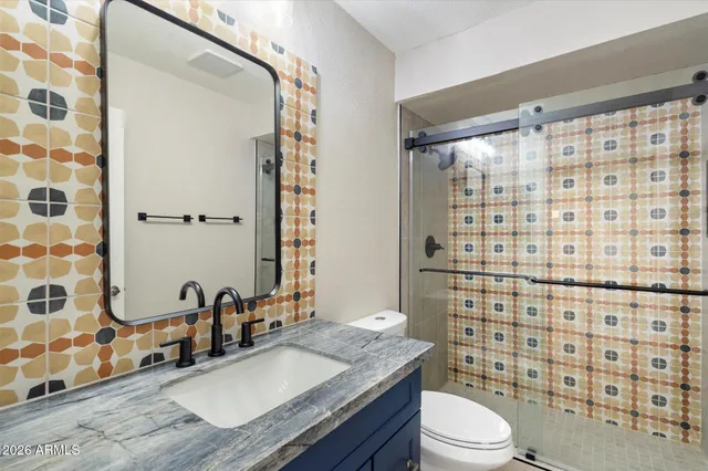 a bathroom with a granite countertop sink a toilet and shower
