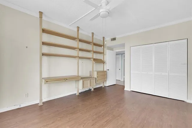 an empty room with wooden floor closet and windows