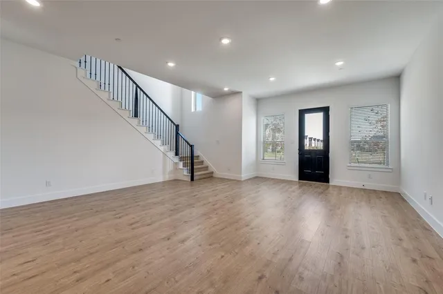 a view of an empty room with wooden floor stairs