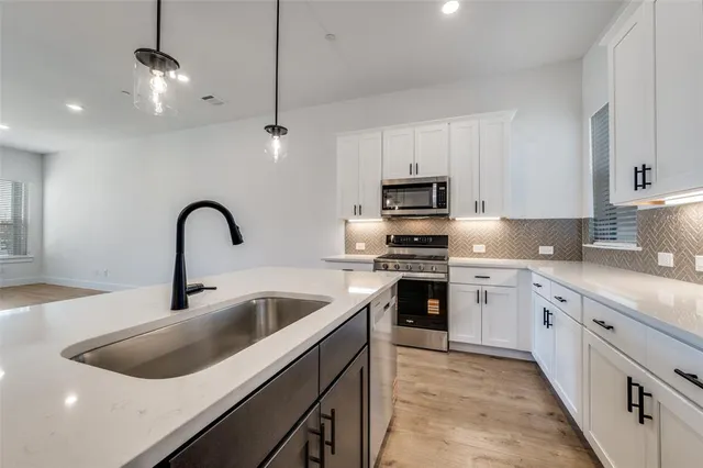 a kitchen with stainless steel appliances granite countertop a sink a stove and a refrigerator