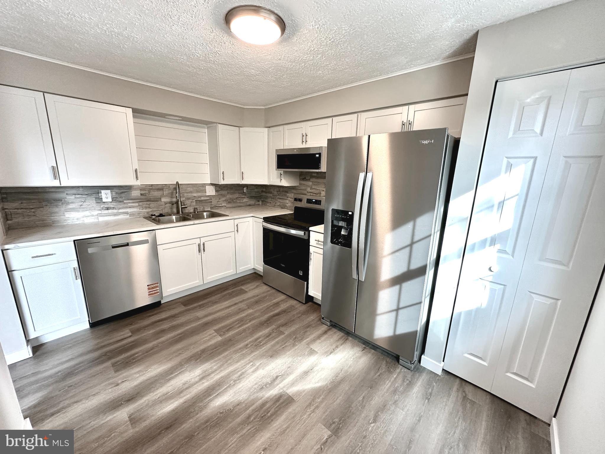 1776 Springfield Lane Frederick, MD 21702 - Photo 17 of 56 a kitchen with stainless steel appliances hardwood floor sink and wooden cabinets