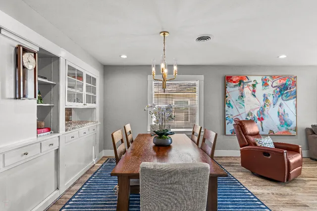a dining room with wooden floor a chandelier a wooden table and chairs