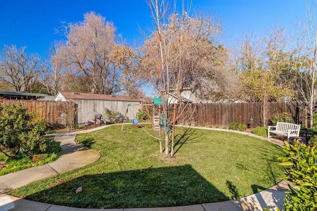 a view of an house with backyard and a tree