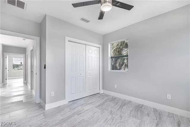 an empty room with wooden floor fan and windows