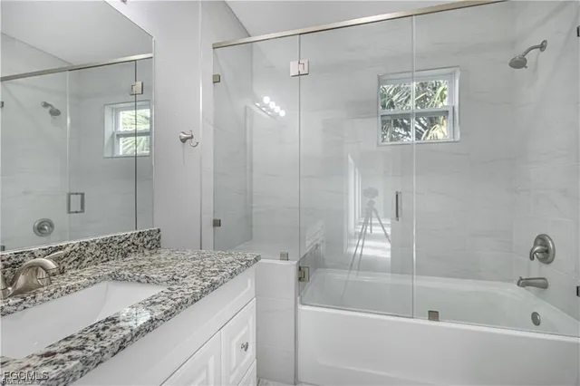 a bathroom with a granite countertop sink a mirror a bathtub and shower