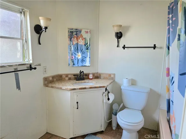 a bathroom with a granite countertop toilet sink and mirror