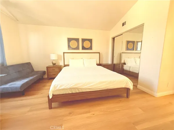 a bedroom with a bed painting on wall and a potted plant
