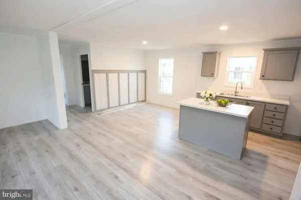 a large white kitchen with wooden floors and stainless steel appliances