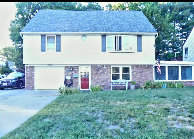 a front view of house with yard and trees in the background