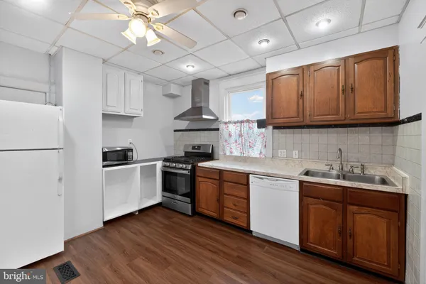 a kitchen with stainless steel appliances granite countertop a sink a stove a refrigerator cabinets and wooden floor