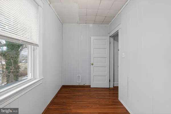 a view of an empty room with wooden floor and a bathroom