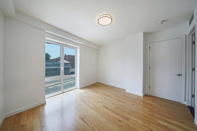 an empty room with wooden floor and window