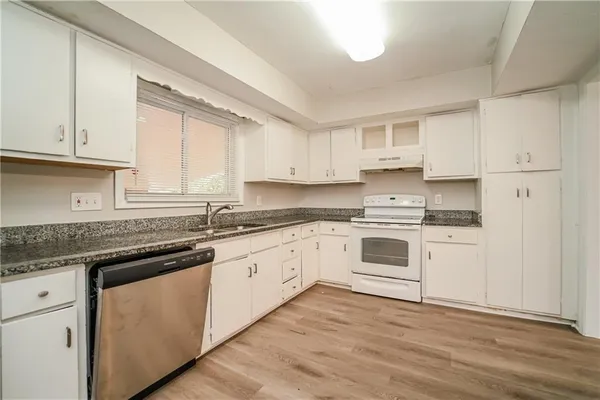 a white kitchen with granite countertop stainless steel appliances