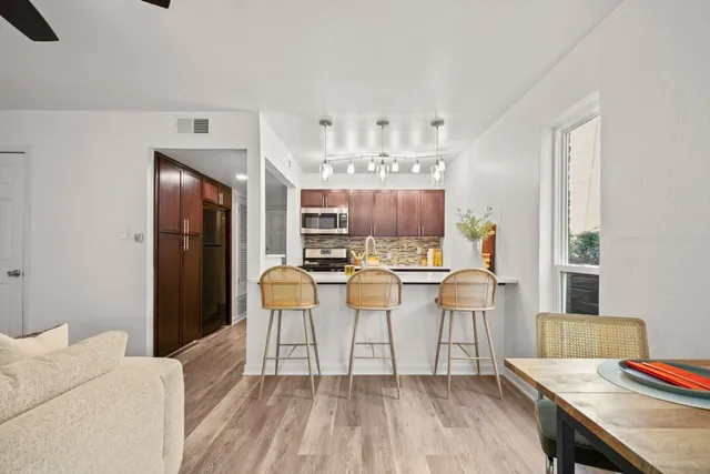 a living room with stainless steel appliances kitchen island granite countertop furniture and a wooden floor