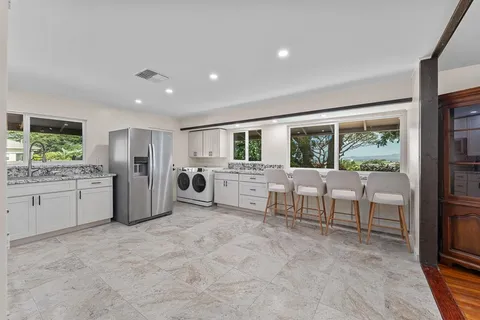 a large white kitchen with a stove a sink dishwasher a refrigerator with a dining table and chairs