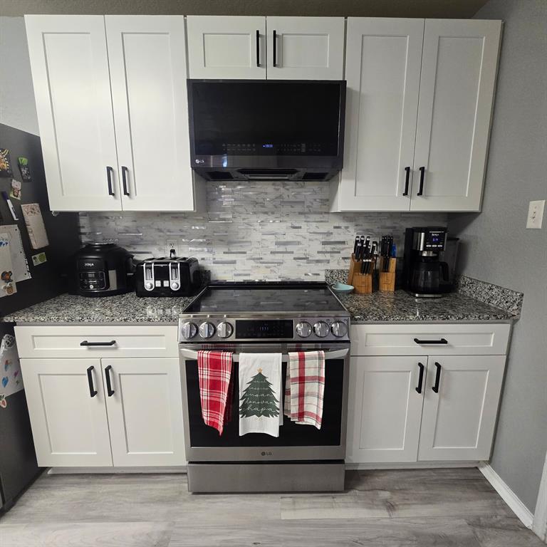 212 Druse Lane Jarrell, TX 76537 - Photo 25 of 38 a kitchen with stainless steel appliances granite countertop a stove a microwave and cabinets