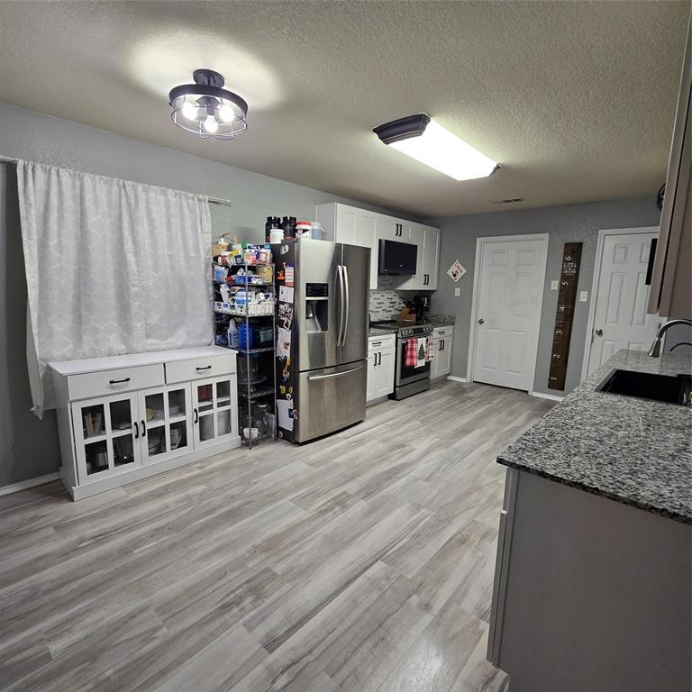 212 Druse Lane Jarrell, TX 76537 - Photo 8 of 38 a open kitchen with stainless steel appliances granite countertop a refrigerator oven a stove and a wooden floors