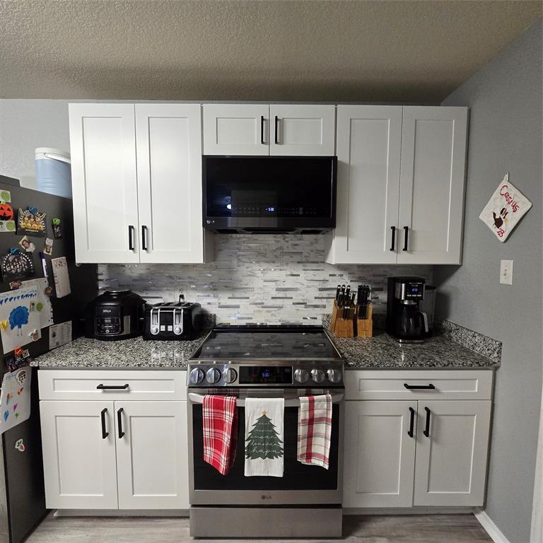212 Druse Lane Jarrell, TX 76537 - Photo 10 of 38 a kitchen with stainless steel appliances granite countertop a stove a sink and a microwave