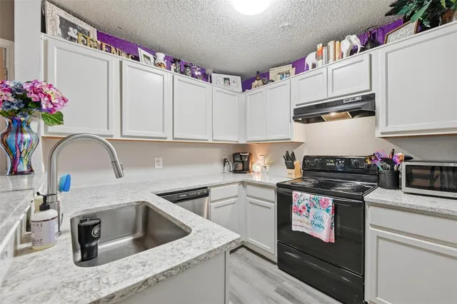 a kitchen with white cabinets and sink