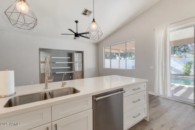 a kitchen with a sink a chandelier and living area view
