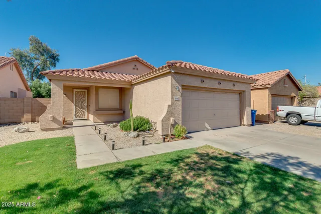a view of a house with a yard and table and chairs under an umbrella