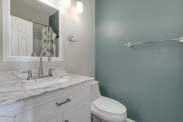 a bathroom with a granite countertop sink toilet and a mirror