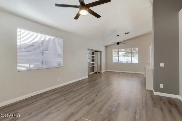 a view of an empty room with a window and wooden floor