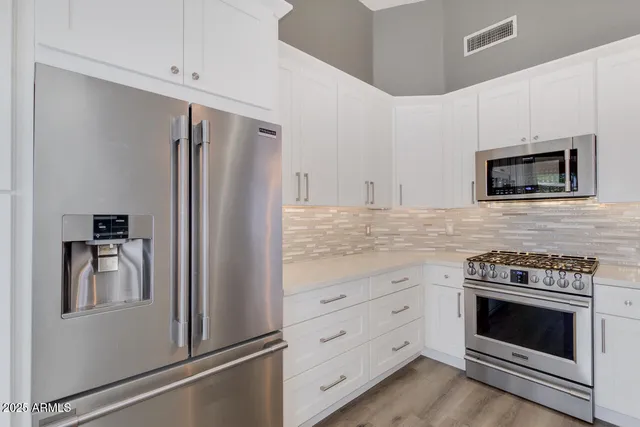 a kitchen with white cabinets and stainless steel appliances