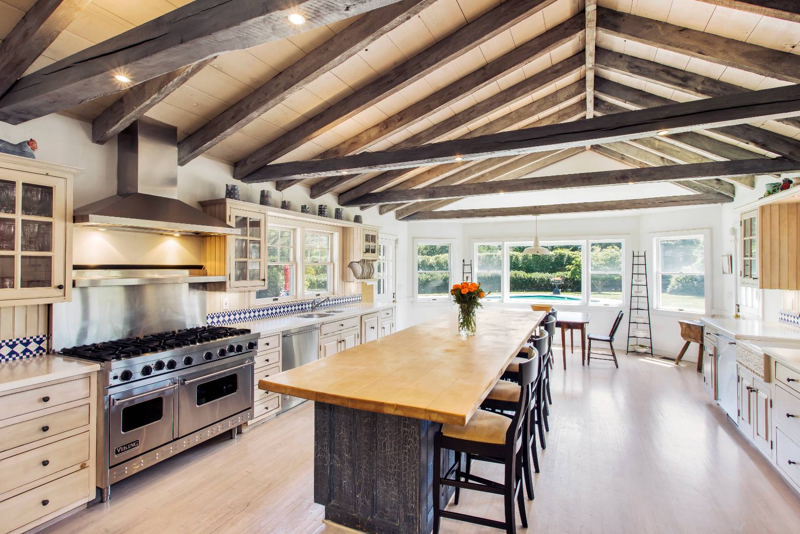 227 Sagaponack Road Bridgehampton, NY 11932 - Photo 4 of 26 a kitchen with stainless steel appliances a stove a table and chairs with wooden floor