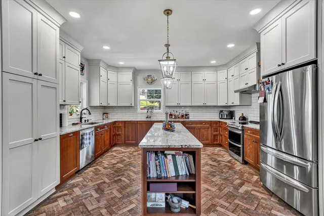 a kitchen with stainless steel appliances granite countertop a refrigerator a sink dishwasher a stove and white cabinets with wooden floor