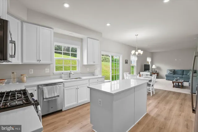 a dining room with wooden floor a chandelier a glass table and chairs
