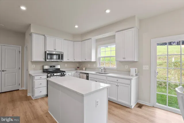 a kitchen with kitchen island granite countertop a stove a sink a refrigerator a dining table and chairs