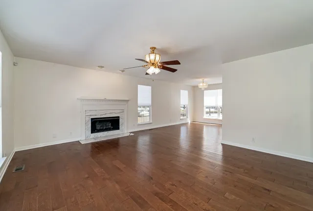 a view of an empty room with wooden floor fireplace and a window