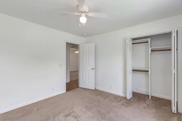 an empty room with closet and a ceiling fan