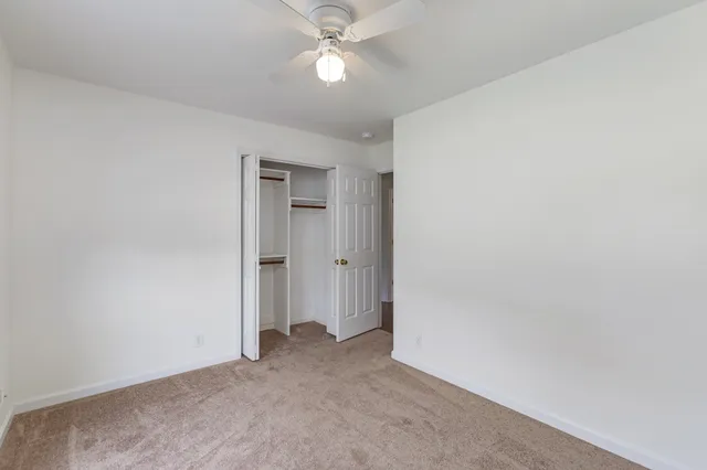 an empty room with closet and a ceiling fan