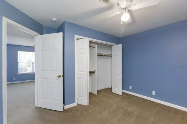 an empty room with a bathroom and a chandelier fan
