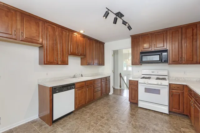 a kitchen with stainless steel appliances granite countertop wooden cabinets a stove a sink and dishwasher