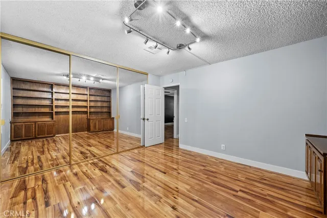 a view of an empty room with wooden floor and a ceiling fan