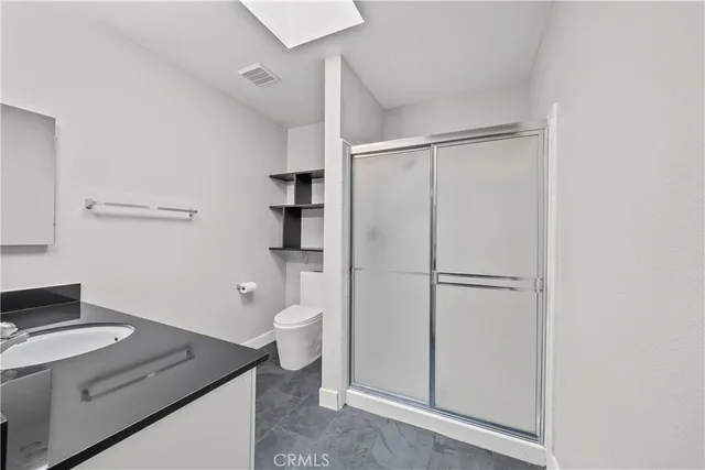 a bathroom with a granite countertop sink vanity mirror and toilet