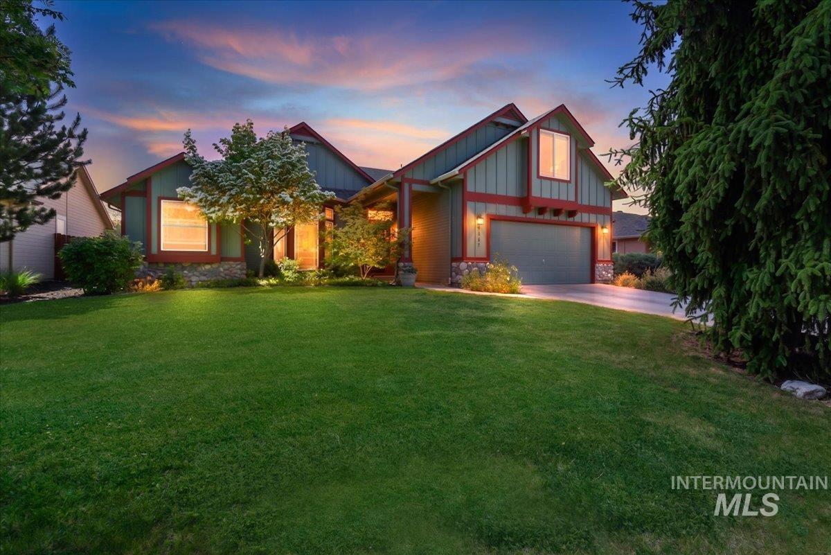 Inviting Craftsman-style home featuring a two-car garage, mature landscaping, and a stone facade foundation