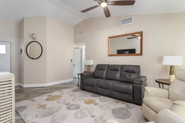 a living room with furniture a ceiling fan and a rug