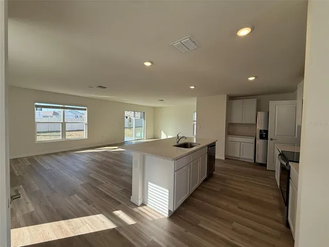 a large white kitchen with wooden floor and a sink