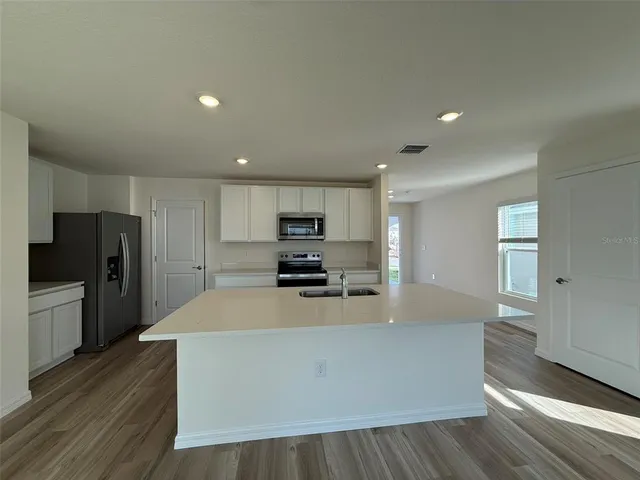a large kitchen with stainless steel appliances a large counter top and wooden floors