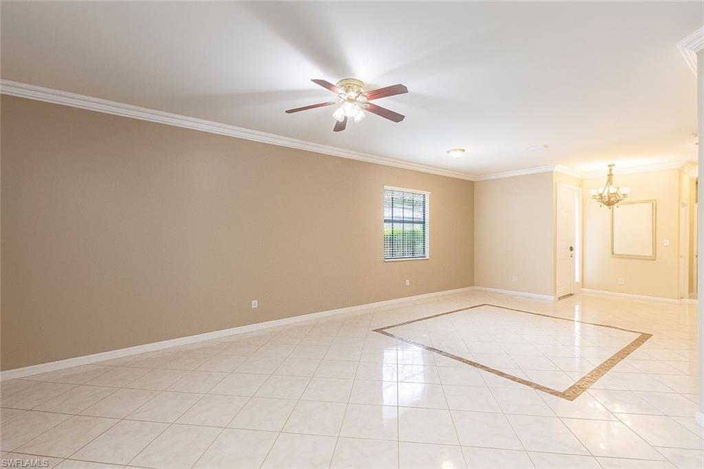 Spare room with crown molding, light tile patterned floors, ceiling fan, and a chandelier
