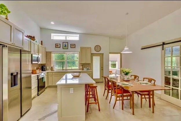a kitchen with stainless steel appliances granite countertop table chairs and a refrigerator