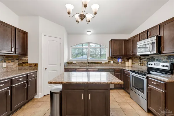 a kitchen with stainless steel appliances granite countertop a stove top oven a sink dishwasher a dining table and chairs with wooden floor